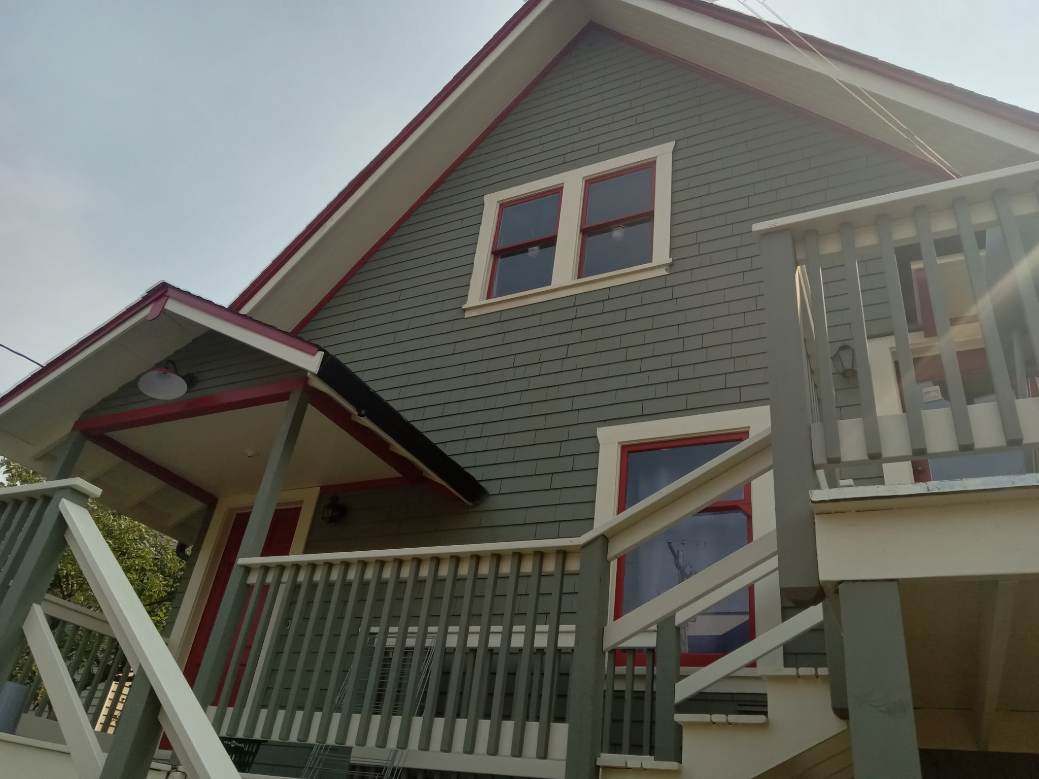 Finished exterior painting with red trim and white window frames